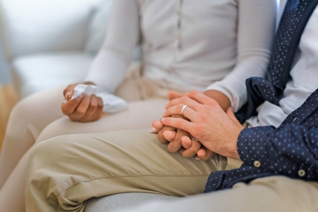 A hand holding tissue of a couple sit on sofa