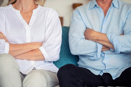 Older couple sitting on couch with arms crossed