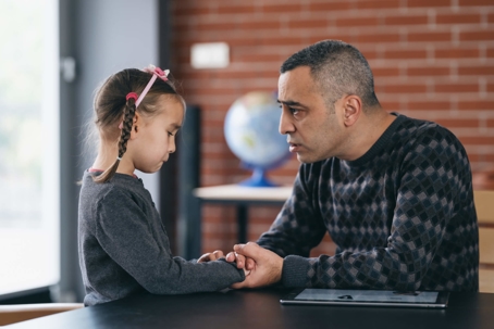 Father holding hands with crying daughter