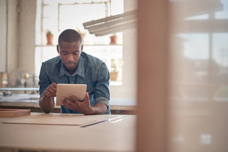 Man looking at his tablet  standing at table